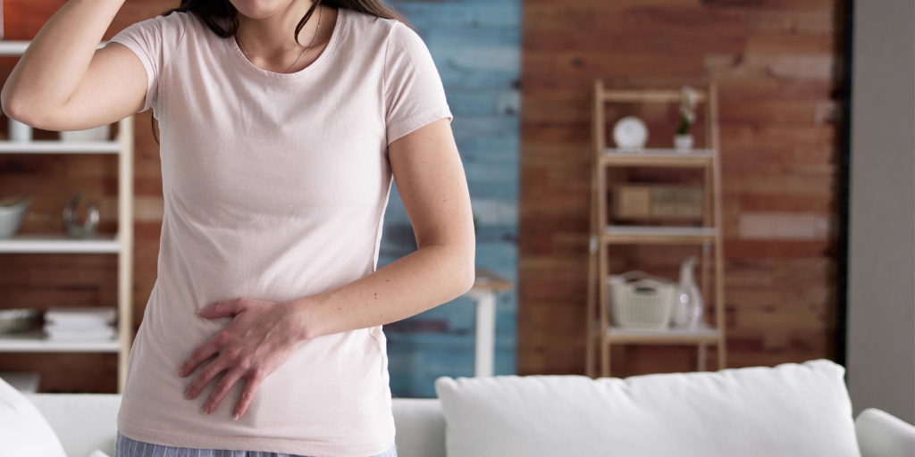 Woman holds her abdomen in apparent discomfort