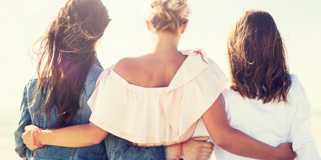 3 women place arms around each other supportively