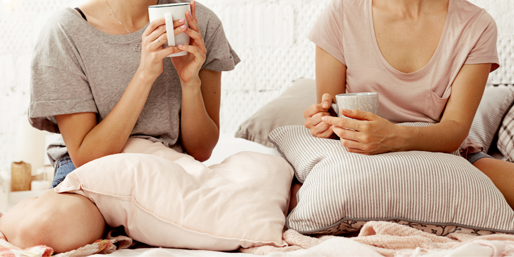 Two young women chat while having coffee in a cozy, home setting