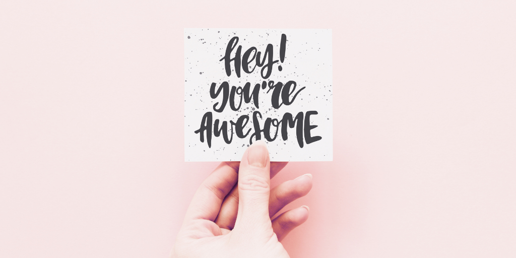Hand holds a note that reads, "Hey! You're awesome"