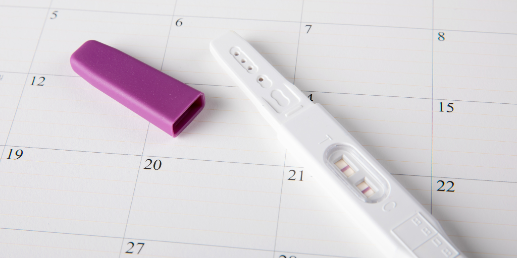 Can I get pregnant during my period? Pregnancy test laying on calendar 